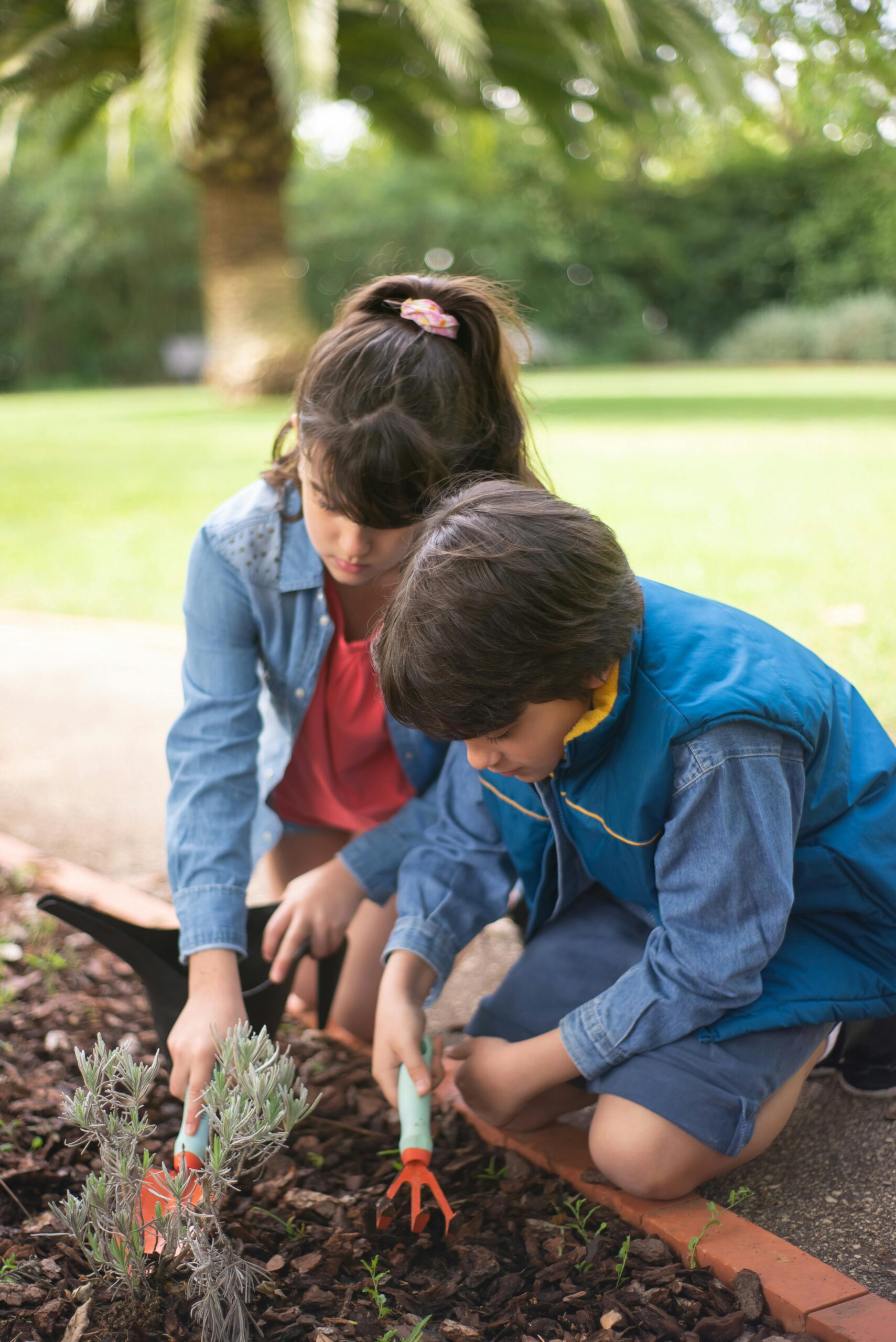 Two children gardening outdoors in Portugal, engaging with soil and plants.